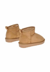 Stivali alla caviglia in suede tan con fodera morbida, punta tonda e suola piatta in gomma. Presentano un anello posteriore per una facile calzata.
