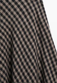 Tissu à carreaux noirs et beiges avec une texture visible et des plis en motif diagonal sur une surface textile douce.