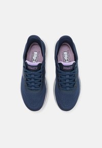 Navy blue sneakers feature a breathable mesh upper, lace-up design, and a padded insole with light purple accents. White sole.