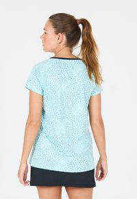 Ljusblå t-shirt med en texturerad, leopardmönstrad design. Kortärmad och med svart halsringning. Parat med en svart kjol.