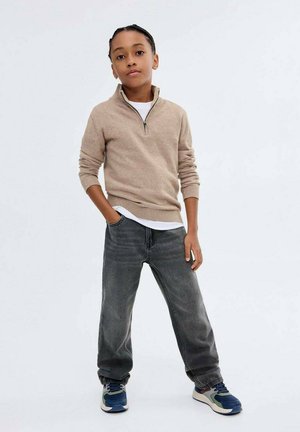 Beige zip-up tröja, vit skjorta under och grå jeans. Blå och gröna sneakers fulländar-outfitten. Rakt ben, avslappnad stil.