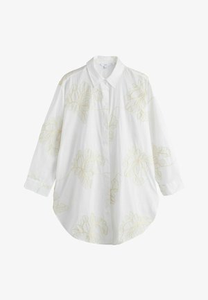 Fehér hosszú ujjú gombos ing hegyes gallérral, halvány sárga virágos hímzéssel az elején és az ujjakon.