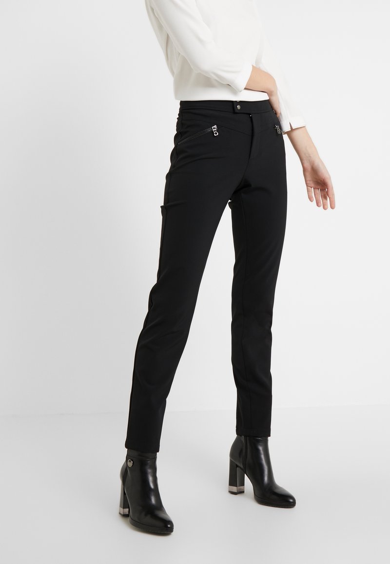 Svarta skräddarsydda byxor med slim fit och framfickor med dragkedja, kombinerat med svarta höga ankelstövlar. Slät tyg och minimalistisk design.