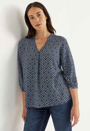 Blå mönstrad blus med V-halsringning, trekvartslånga ärmar, som har en geometrisk bladdesign i ljusblått och marinblått. Mjuk tygtextur.