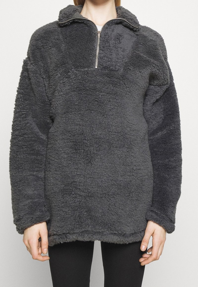Grauer Fleece-Pullover mit hohem Kragen und halbem Reißverschluss. Strukturiertes Gewebe mit einem plüschigen, weichen Finish und überschnittenen Schultern für eine lockere Passform.