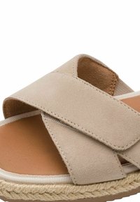 Sandale en daim beige avec de larges brides croisées, semelle intérieure rembourrée couleur tabac et bord de semelle en jute tressé.