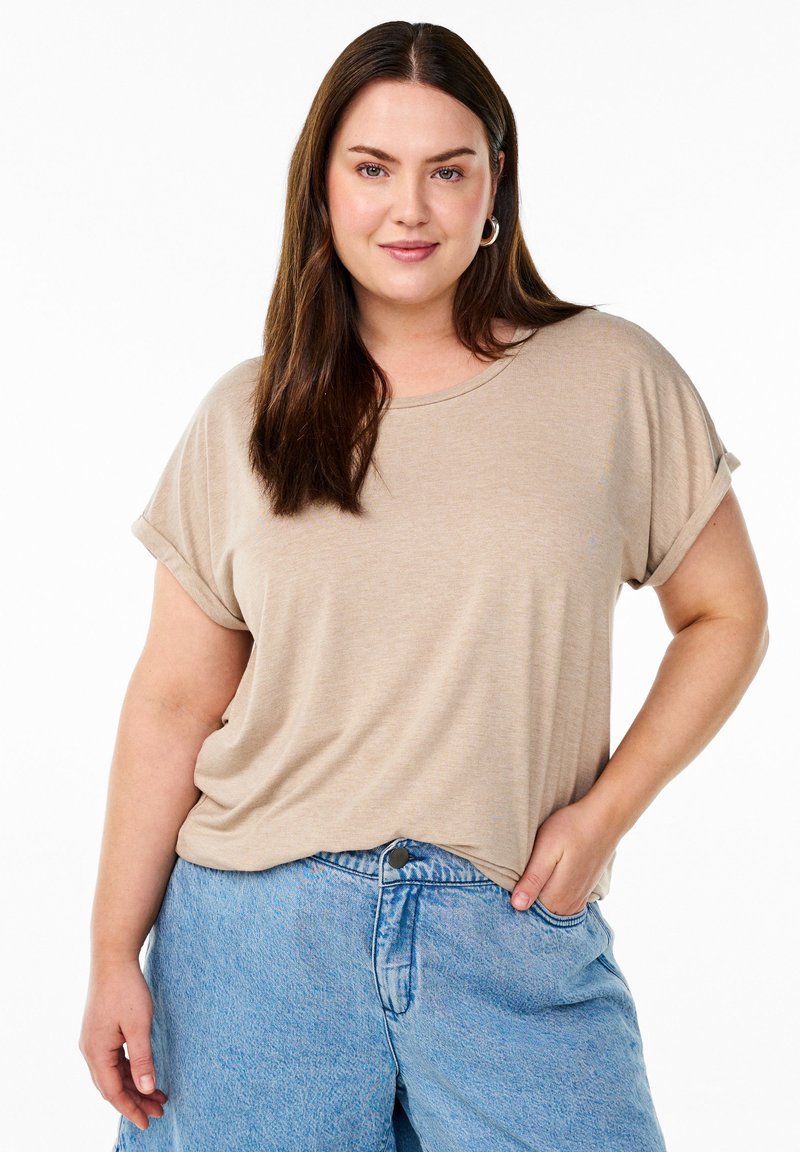 Beige Baumwoll-T-Shirt mit kurz gerollten Ärmeln, lässiger Schnitt, runder Halsausschnitt. Kombiniert mit hellblauen Denim-Shorts mit Taschen.