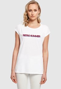 Tricou alb din bumbac cu mâneci rulate și un grafic retro "RETRO SUMMER" în litere îndrăznețe roșii și violet.