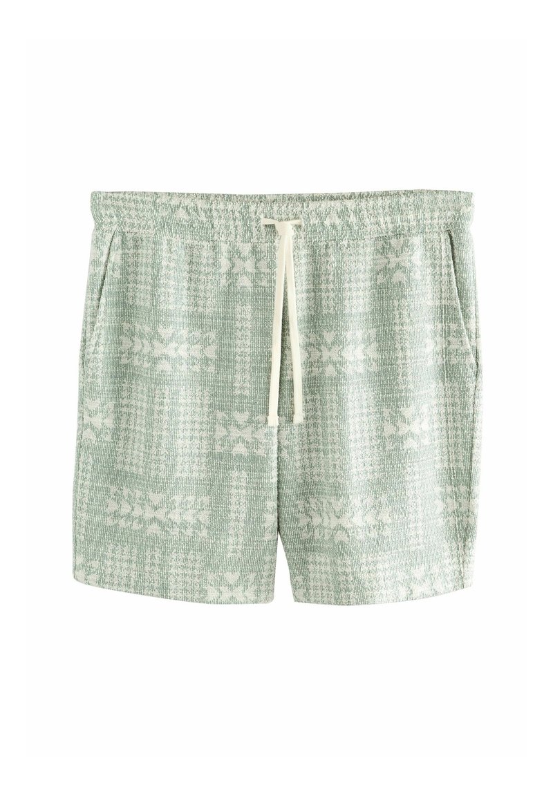 Costumi da bagno verde chiaro con motivo, dotati di una vita elasticizzata e un cordino, realizzati in un tessuto testurizzato e decorati con disegni floreali bianchi.