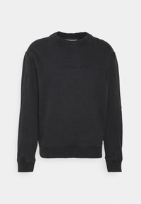 Černá mikina s kulatým výstřihem vyrobená z měkké tkaniny s žebrovanými manžetami a lemem. Na přední straně je vyražené logo "Calvin Klein Jeans". Normální střih.
