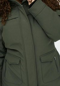 Olivgrön isolerad jacka med hög krage, dragkedjestängning, två framfickor och svarta detaljer vid ärmsluten.