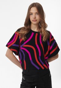 Top negro de manga corta con rayas texturizadas de colores en rojo, púrpura y rosa, con un corte relajado y mangas anchas.