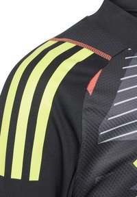 Zwart sportshirt met gele en oranje strepen, honingraattextuur en grafische patronen op de stof voor verbeterde zichtbaarheid.