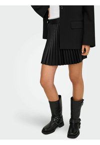 Must mustriga seelik siledaga vööga, kombineeritud põlvekõrguste mustade nahast saapadega, millel on pannal ja rõngasaktsent.