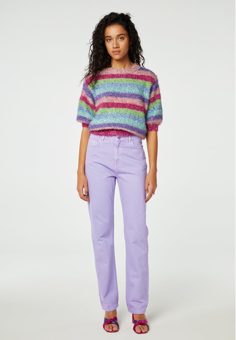 Multikleurige pluche trui met horizontale strepen in roze, blauw, groen en rood. Gekoppeld met lavendel rechte broek en roze sandalen.