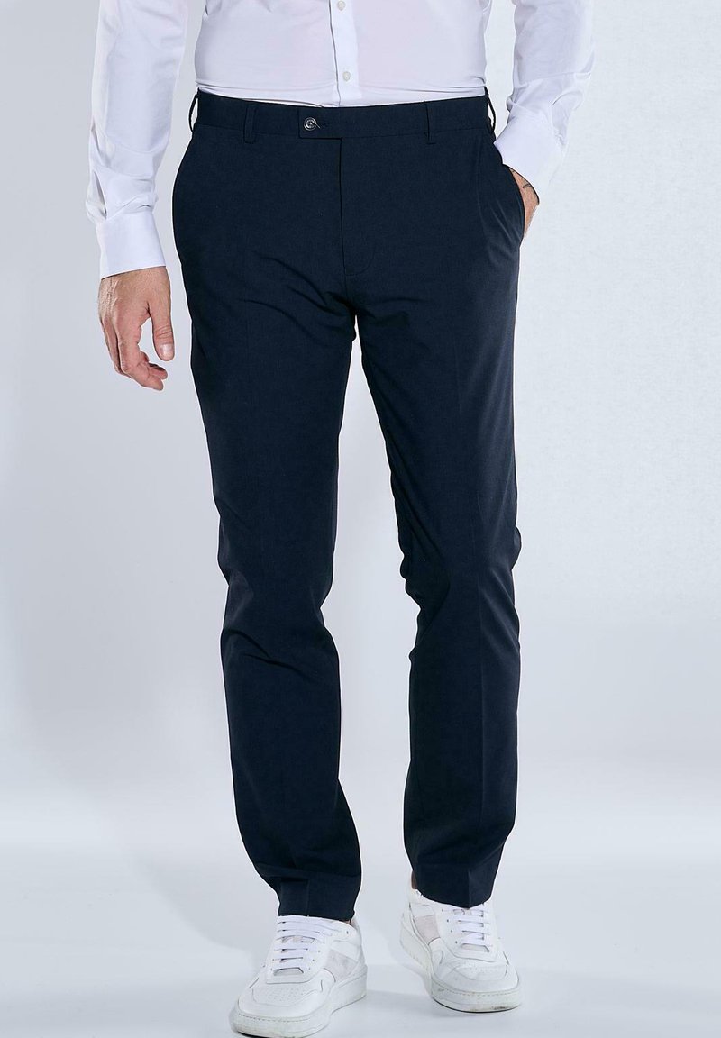 Dark navy trousers with a slim fit design, made from smooth fabric. Features front pockets and subtle branding on the waistband.