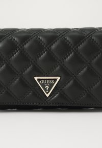 Borsa in ecopelle trapuntata nera con logo triangolare in tonalità oro. Pattern a diamante testurizzato con cuciture nere. Forma rettangolare.