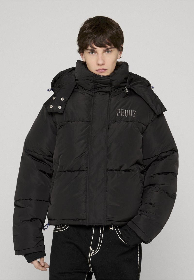 Črna puhovka z visokim ovratnikom, s prešitim dizajnom, sprednjim zadrgo in izvezenim logotipom "PEOUS". Strukturiran material in podrobnosti.