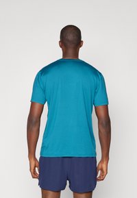 Teal t-shirt met korte mouwen, een ronde hals, een zachte textuur en een relaxte pasvorm, gedragen met marineblauwe shorts. Achteraanzicht weergegeven.