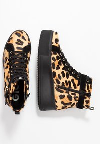 Leopardi-kuosi korkeat tennarit, joissa on musta kumipohja, nahka-akkentit, kultaiset silmukkakiinnitys, ja sivuvetoketjuyksityiskohta helppoa pääsyä varten.