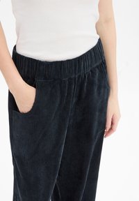 Spodnie z korduroy w ciemnym granacie z teksturowanym pionowym prążkiem, z elastycznym pasem i bocznymi kieszeniami.