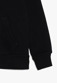 Schwarzer Pullover mit Kängurutasche, gerippten Bündchen und Saum, gefertigt aus weichem Stoff mit dezenten Nahtdetails.