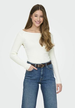 Geribbelde witte langesleeve top met een off-shoulder ontwerp, gecombineerd met hoge taille blauwe jeans en een bruine riem met een ronde gesp.