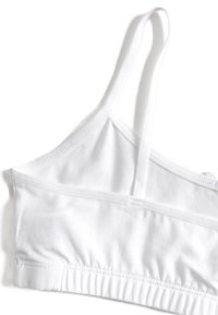 Vit bomullsbralette med justerbara band, sömlös design, mjuk textur och elastisk kant nederst för komfort och passform.