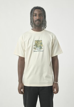 Cream-colored cotton T-shirt featuring a graphic print in green. Loose fit, round neck, short sleeves, and minimalistic design.