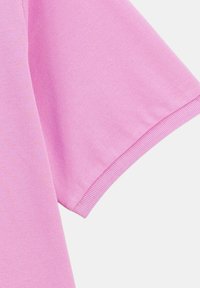 Tissu rose à manches courtes montrant la texture et les détails de couture, mettant en avant son style décontracté et son matériau léger.