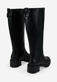 Botas de cuero negro hasta la rodilla con acabado mate, cremallera lateral, paneles elásticos, tacones cuadrados y hebillas metálicas decorativas.