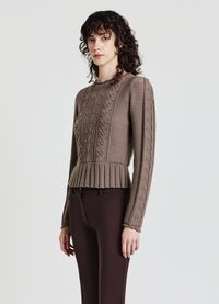 Brauner Strickpullover mit strukturierten Blumenmustern, gerippten Akzenten, einem plissierten Saum und langen Ärmeln, kombiniert mit dunkelbraunen Hosen.