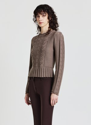 Maglione marrone lavorato a maglia con motivi floreali a rilievo, dettagli a coste, orlo plissettato e maniche lunghe, abbinato a pantaloni marroni scuri.