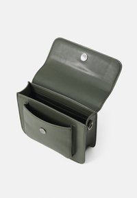 Groene leren schoudertas met een klepsluiting en een drukknoop. Bevat een intern compartiment en een externe voorzak.