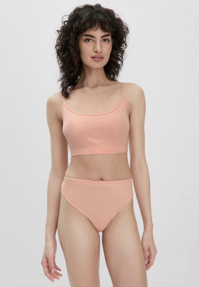 Hellbeige Baumwoll-Bralette mit dünnen Trägern und einem passenden hochgeschnittenen Slip, der ein schlichtes Design und eine weiche Textur aufweist.