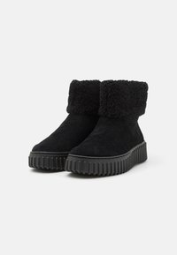 Botas negras hasta el tobillo de ante, con un puño de borreguillo, suela de goma texturizada y un diseño de punta redonda.