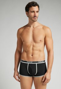 Bóxer negros con banda elástica y acentos grises. Fabricados en un material texturizado, con un ajuste ceñido y un diseño de bolsa contorneada.