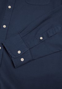 Navyblaue Langarm-Hemd mit Knopfleiste aus Baumwolle, ausgestattet mit einer Brusttasche und hellen Knöpfen an den Manschetten und der Knopfleiste.