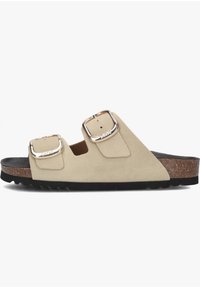 Beige suède sandalen met twee zilverkleurige verstelbare gespen, kurken voetbed en zwarte rubberen zool met een gestructureerd profiel.
