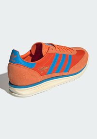 Adidas SL '72 sneakers met oranje suede en textiel bovenwerk, blauwe accenten, drie strepen en een crème rubberen zool. Geweven hiel en tong.