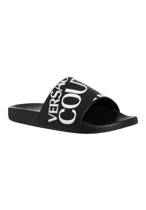Sort slide sandal med åben tå, lavet af glat materiale, der har kontrasterende hvid tekst på den øverste rem. Teksten inkluderer "VERSACE" og "COURT."