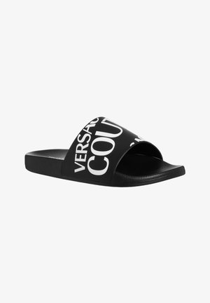 Chancla negra con la punta abierta, hecha de un material suave y con texto blanco en contraste en la correa superior. El texto incluye "VERSACE" y "COURT."