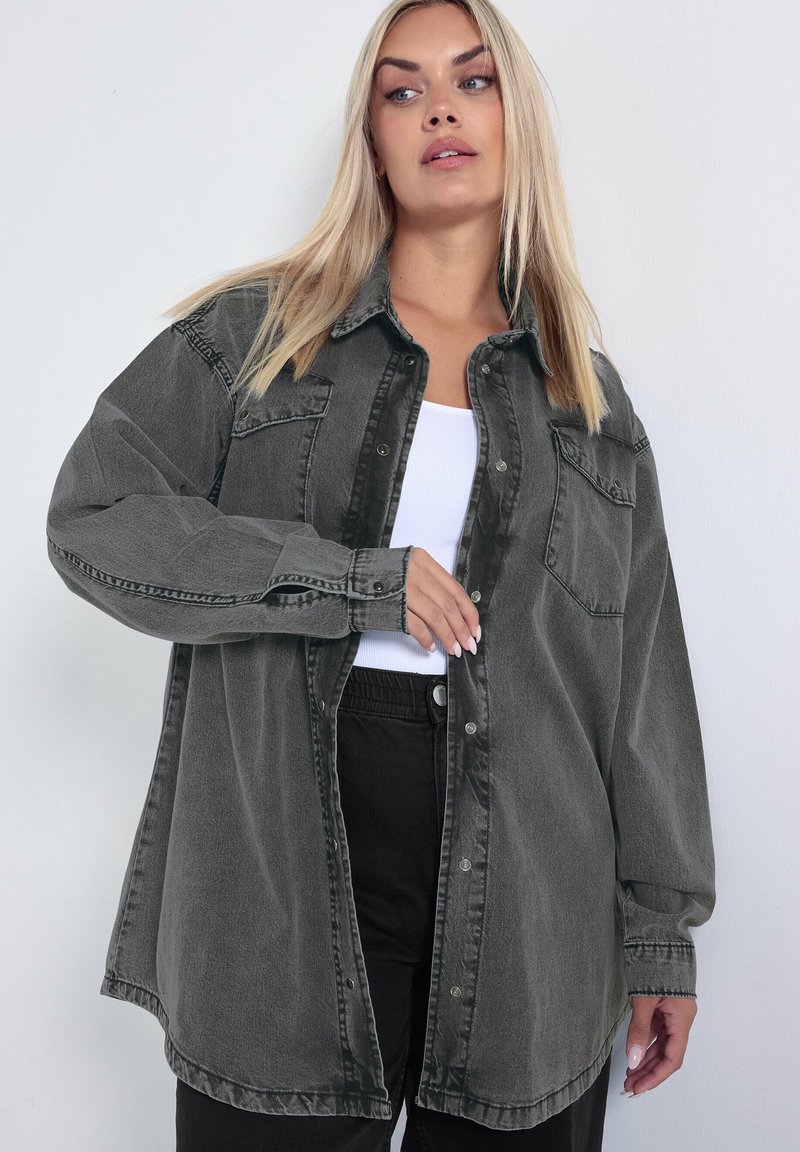 Oversized, ciemnoszara koszula dżinsowa z zapięciem na guziki, szpiczastym kołnierzem oraz dwoma kieszeniami na piersi; lekko wypłowiała tkanina o miękkiej strukturze.