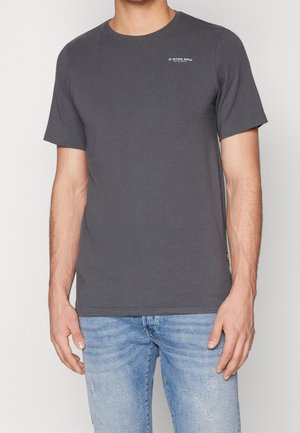 Szara koszulka z krótkim rękawem, wykonana z mieszanki bawełny, z okrągłym dekoltem i detalem logo na piersi. Gładka tekstura i dopasowany fason.