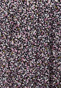 Tessuto nero con una densa stampa floreale composta da piccoli fiori bianchi e rosa, caratterizzato da foglie verdi e delicate arricciature che creano pieghe testurizzate.