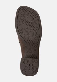 Brown rubber shoe sole with embossed flower and "CAMPER" branding, featuring a flat surface and a heel with the number "38."