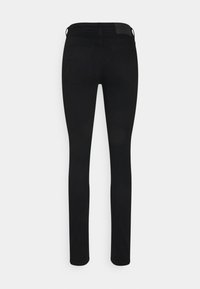 Jeans ajustados negros con una textura suave, que presentan una cintura de tiro medio, bolsillos traseros y un discreto parche de cuero en la cinturilla.