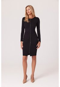 Czarna sukienka z długim rękawem, zapinana z przodu na zamek, dopasowana, do kolan, wykonana z elastycznego materiału, z wyraźnymi szwami i wysokim dekoltem.