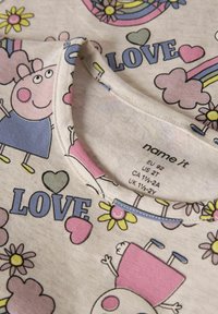 Bawełniany t-shirt z okrągłym dekoltem, z zabawnym nadrukiem kwiatów, serc i postaci w kolorach różowym, niebieskim i żółtym na jasnym tle.