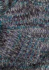 Gros plan sur un tissu tricoté épais avec des fils violets, sarcelle, gris et blancs, montrant un détail de poignet côtelé dans une texture douce et duveteuse.